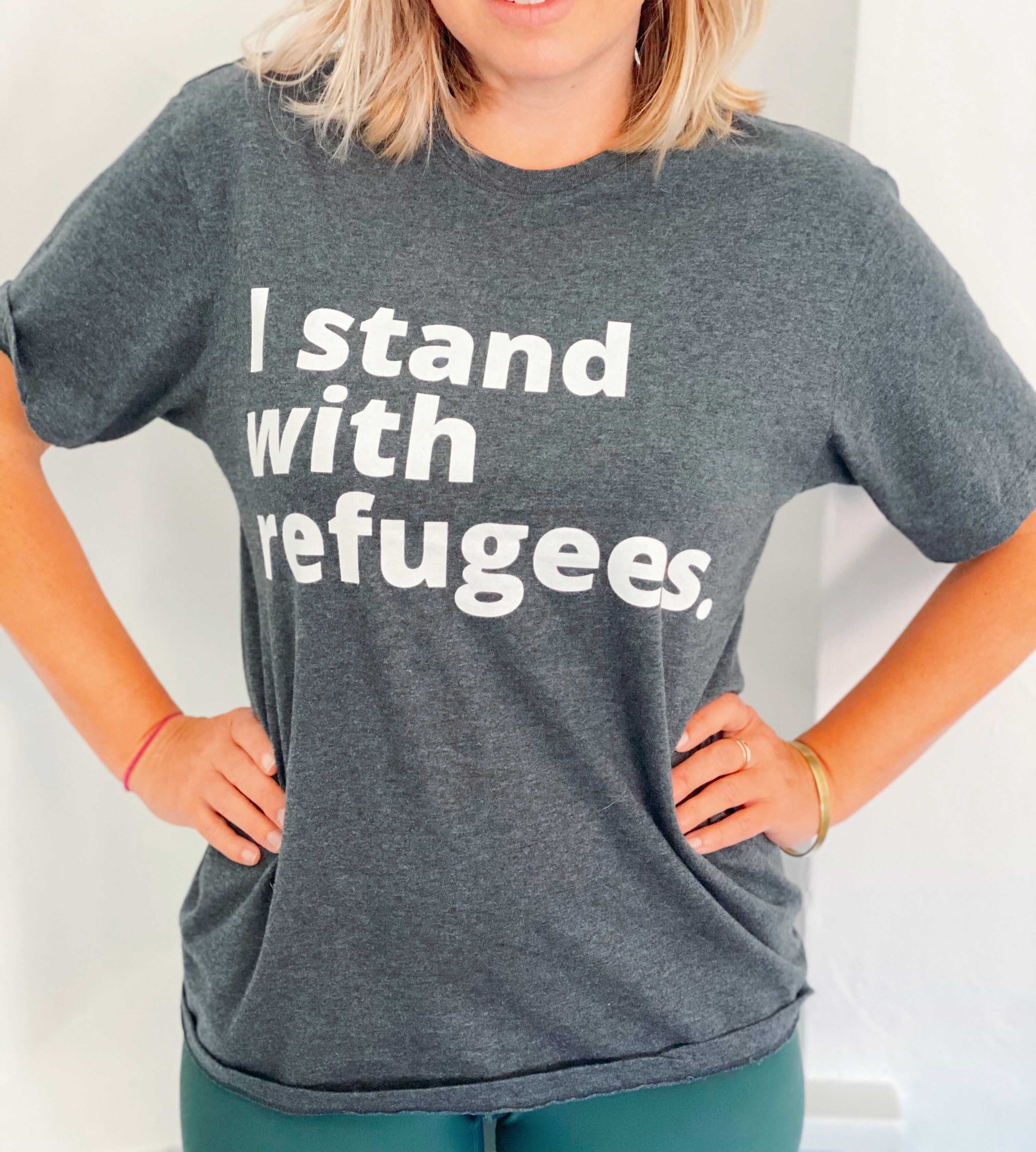 Gray tshirt with white wording "I stand with refugees."